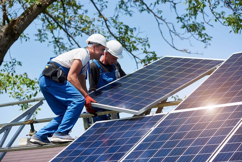 Workers installing solar panel on roof